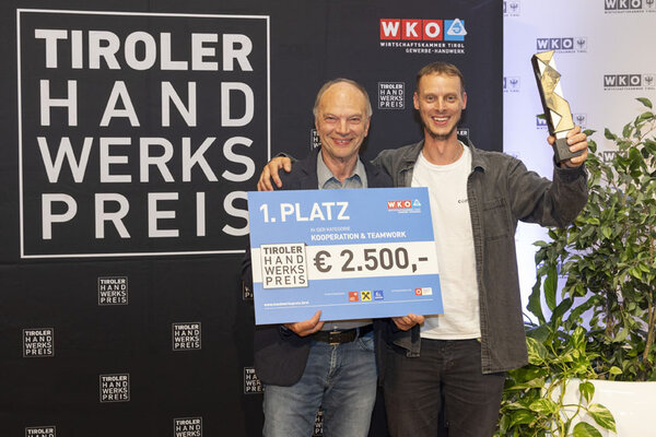 Gewinner mit Scheck und Pokal in der Hand