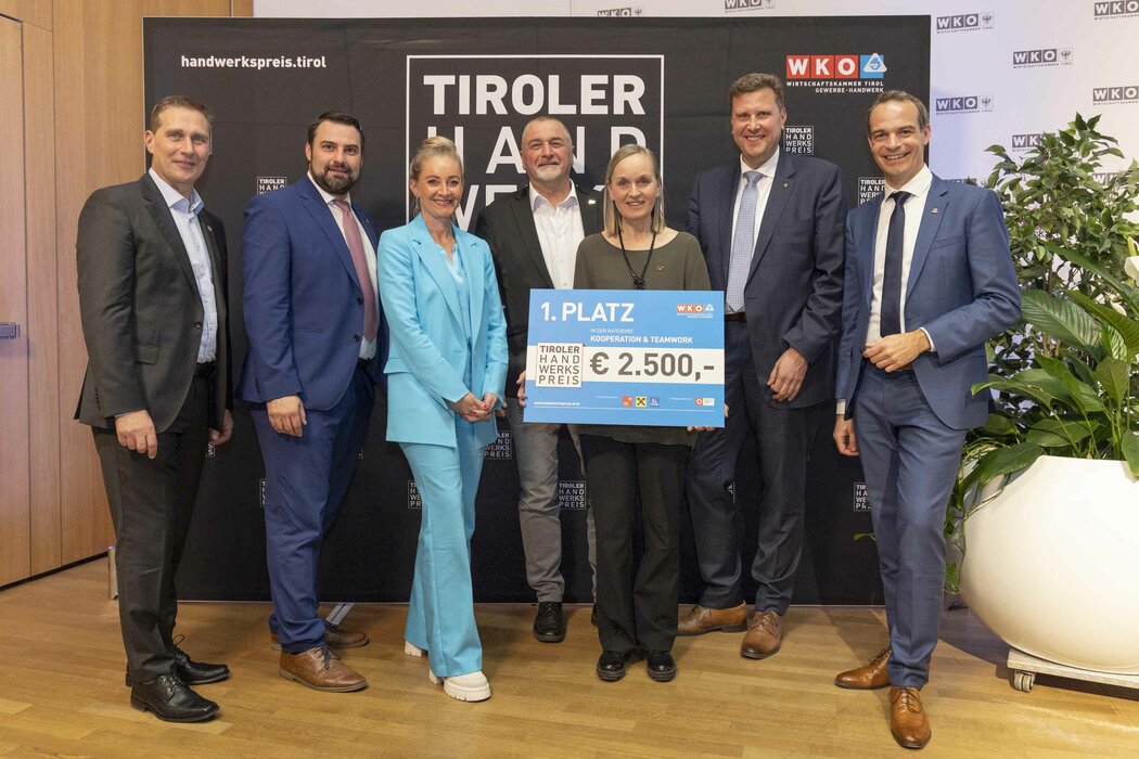 Die Gewinnerin des 1. Platzes 2023 hält einen Scheck in der Hand, links und rechts stehen Funktionäre der WK Tirol.