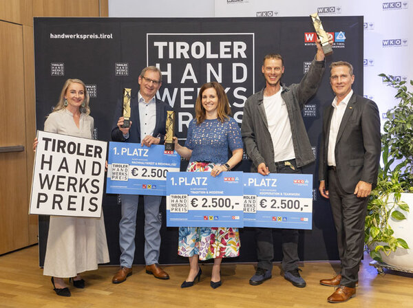 Eine Gruppe von Menschen hält stolz ihre Schecks in die Höhe und zeigt ihre Freude über den 1. Platz in allen Kategorien.