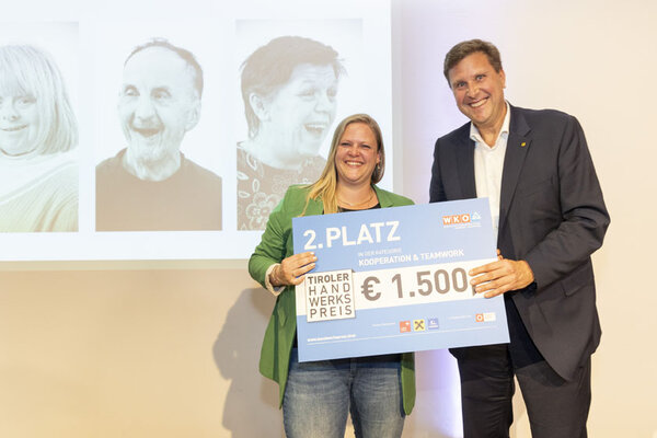 Funktionär und Gewinnerin posieren mit einem Scheck in der Hand