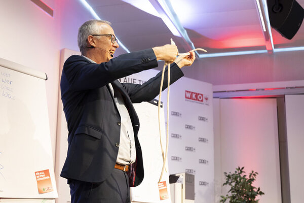 Mann auf einer Bühne hält zwei Seile in der Hand und lacht