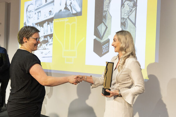 Funktionärin hält Pokal in der Hand und schüttelt Gewinnerin die Hand