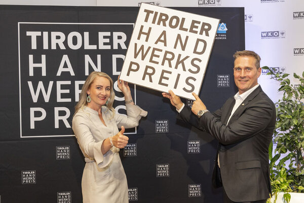 Funktionäre halten das Tiroler Handwerkspreis Logo in der Hand und in die Höhe