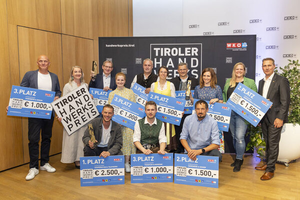 Eine Gruppe von Menschen hält stolz ihre Schecks in die Höhe und zeigt ihre Freude über den Gewinn.