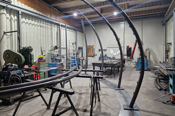 Eine große Metallkonstruktion in einer Werkstatt, umgeben von zahlreichen Werkzeugen und Arbeitsmaterialien.