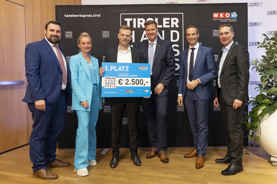 Der Gewinner des 1. Platzes 2023 hält einen Scheck in der Hand, links und rechts stehen Funktionäre der WK Tirol.