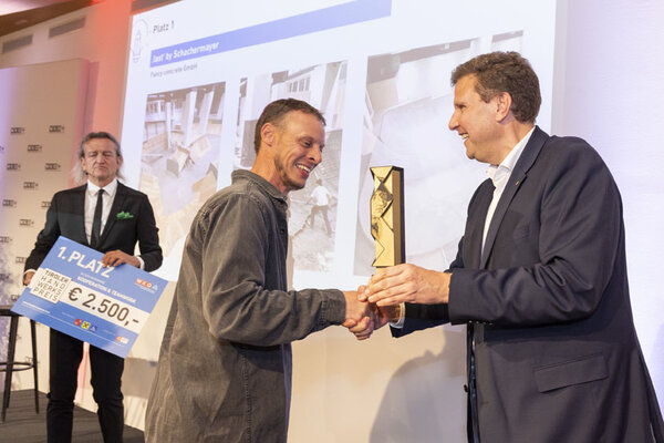 Mann gratuliert Gewinner, schüttelt ihm die Hand und überreicht ihm einen Pokal