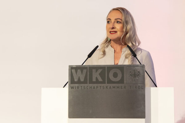 Frau redet auf einem Pult vor einem Publikum