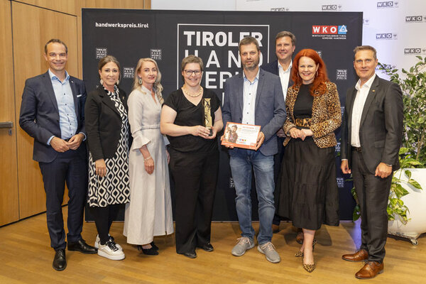 Gewinner mit einem Pokal in der Hand, links und rechts Funktionäre