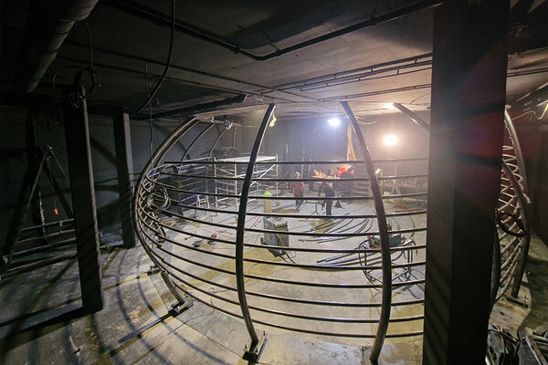 Eine große Metallkonstruktion in einer Werkstatt, umgeben von zahlreichen Werkzeugen und Arbeitsmaterialien.
