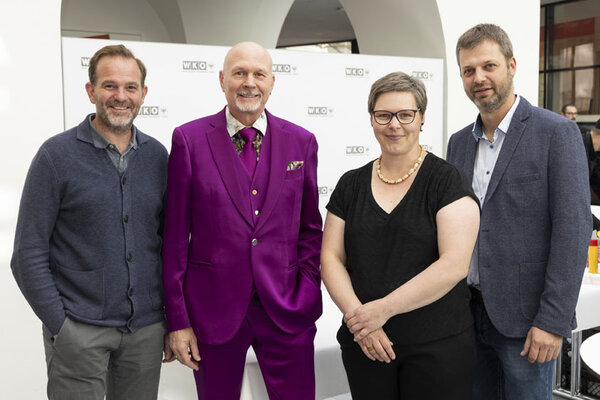 Drei Männer und eine Frau posieren und lachen in die Kamera