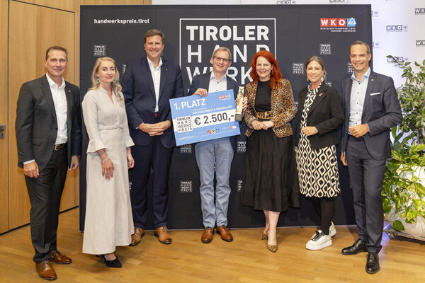 Gewinner mit einem Scheck in der Hand, links und rechts Funktionäre
