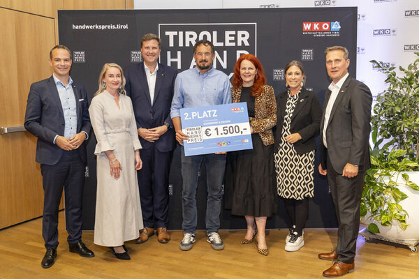 Gewinner mit einem Scheck in der Hand, links und rechts Funktionäre