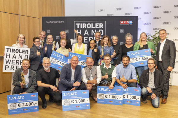 Eine Gruppe von Menschen hält stolz ihre Schecks in die Höhe und zeigt ihre Freude über den Gewinn.