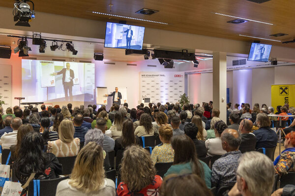 Viele Menschen in einem Saal schauen auf einen Redner