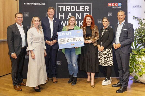 Gewinner mit einem Scheck in der Hand, links und rechts Funktionäre