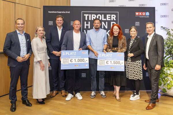 Gewinner mit einem Scheck in der Hand, links und rechts Funktionäre