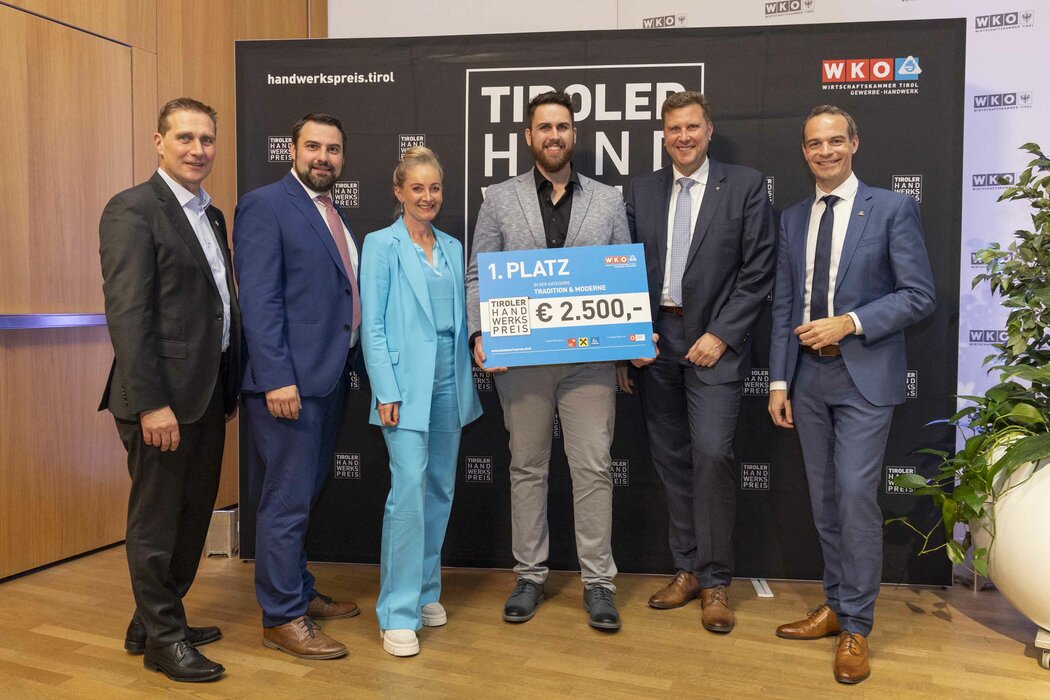 Der Gewinner des 1. Platzes 2023 hält einen Scheck in der Hand, links und rechts stehen Funktionäre der WK Tirol.