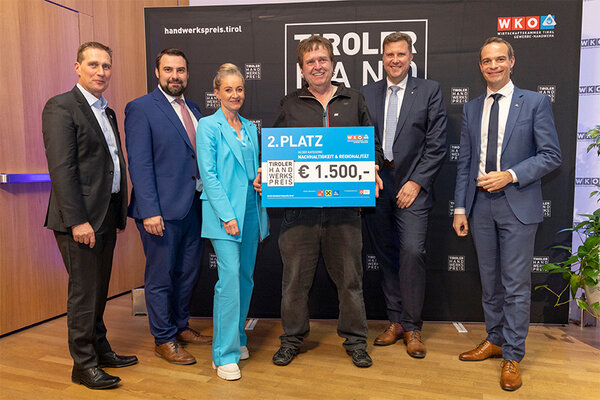Der Gewinner zeigt seinen Scheck mit Funktionären der Wirtschaftskammer Tirol.