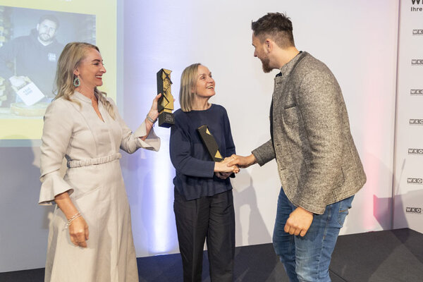 Funktionär schüttelt Frau die Hand. Funktionärin hält Pokal in der Hand