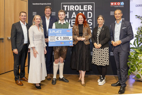Der Gewinner hält stolz seinen Scheck in die Höhe und zeigt seine Freude über den 3. Platz in der Kategorie Tradition & Moderne.