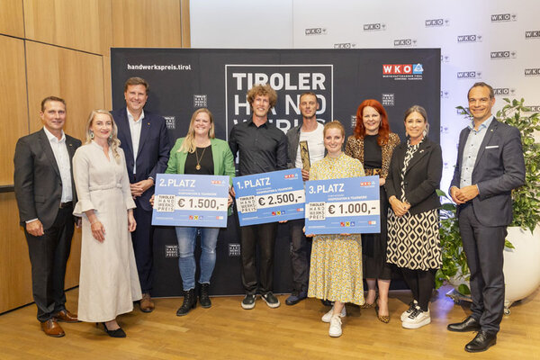 Gewinner mit einem Scheck in der Hand, links und rechts Funktionäre