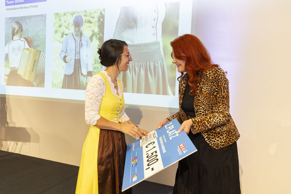 Frau überreicht Gewinnerin einen Scheck