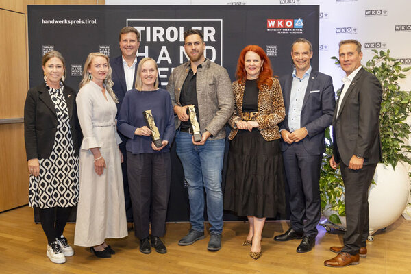 Gewinner mit einem Pokal in der Hand, links und rechts Funktionäre