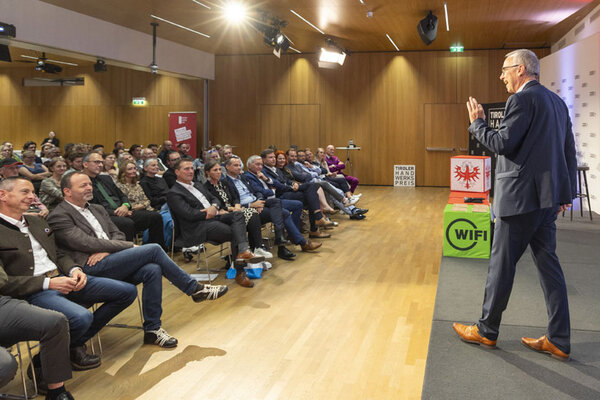 Viele Menschen in einem Saal schauen auf einen Redner