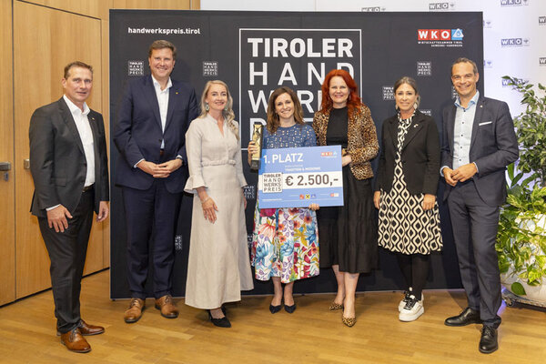 Die Gewinnerin hält stolz ihren Scheck und Pokal in die Höhe und zeigt ihre Freude über den Gewinn in der Kategorie Tradition & Moderne.